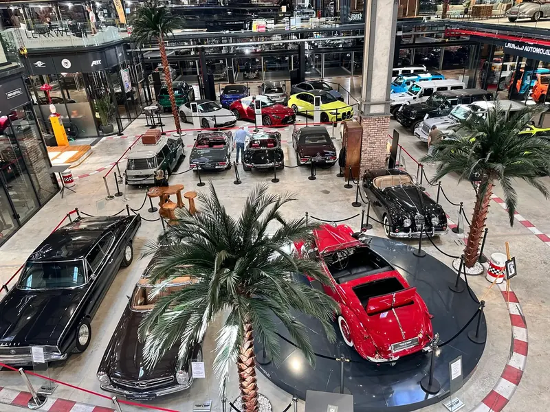 Sala de exposición de Motorworld con clásicos y palmeras